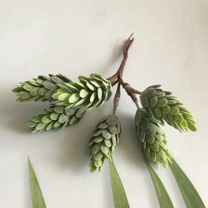 Artificial green pinecone branch with textured layered scales and brown stem in frosted greenery berry stamen bundle decorbites greenery berry
