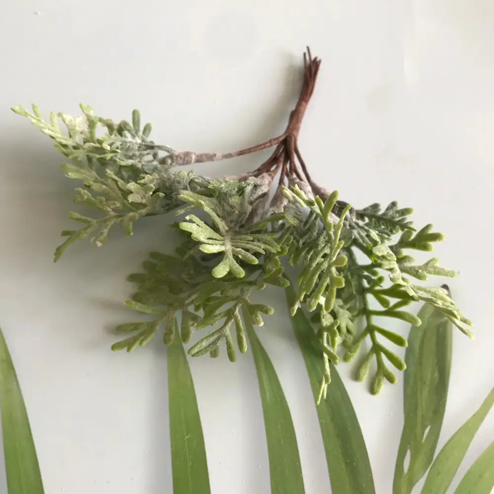 A delicate artificial green fern sprig with frost-dusted leaves and brown stem in a frosted greenery berry stamen bundle
