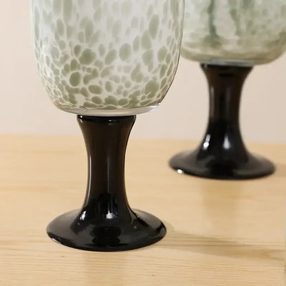 Elegant green and white speckled glass wine goblets with sleek black stems featuring dot texture decorbites dot texture design