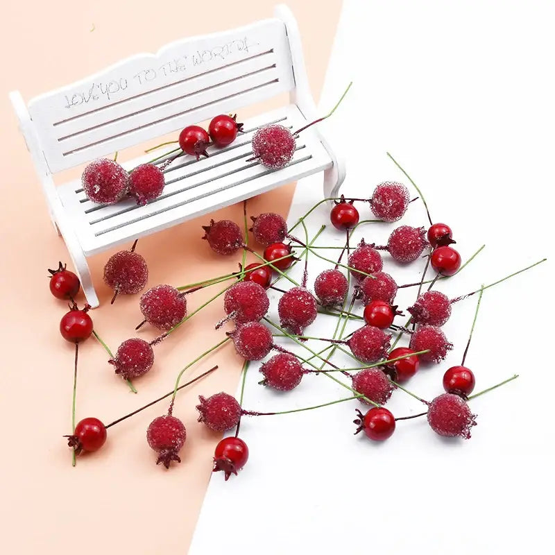 Frosted red foam cherry artificial fruits with green stems and dark calyxes scattered around a white bench decorbites foam cherry