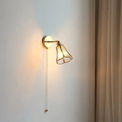 Gold-toned wall sconce with fluted glass shade and adjustable arm complements geometric amber and cream glass pendant light for dining room