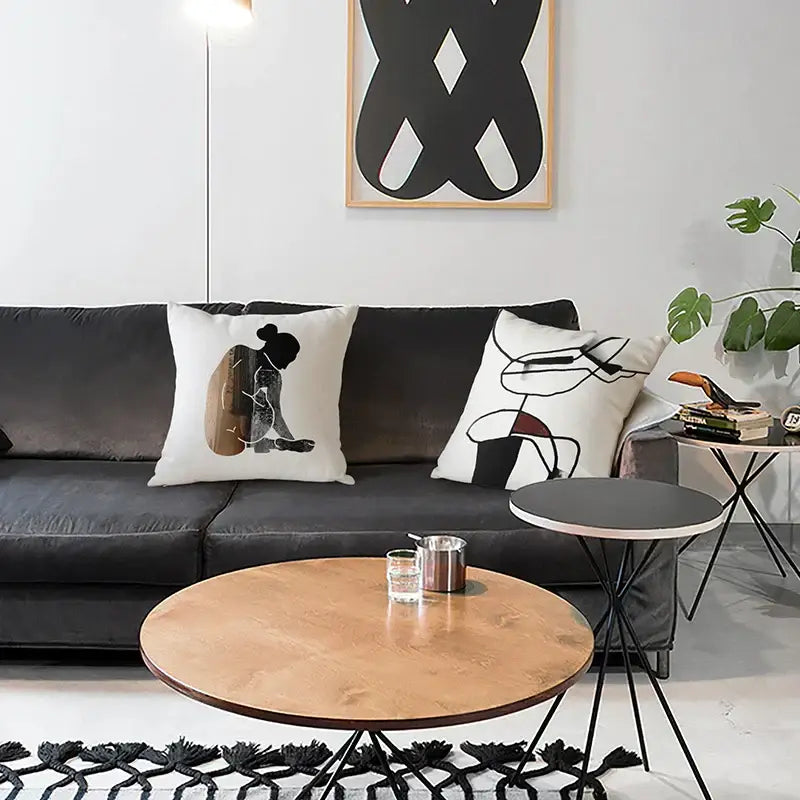 Black velvet geometric artist sofa with two white cushion covers featuring abstract black and brown silhouettes decorbites decor