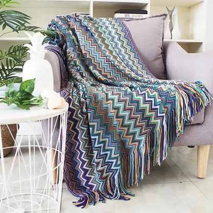A vibrant geometric aztec baja knit throw blanket in mustard and blue with fringe detailing for living room decorbites