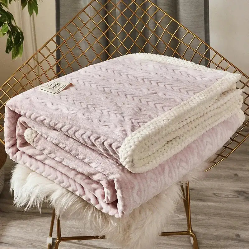A blush pink plush throw blanket with textured chevron pattern and cream knitted border made of coral fleece flannel