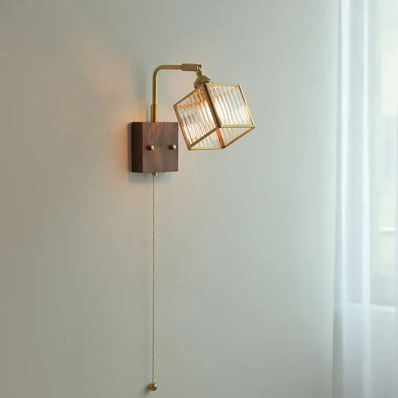 Brass led wall light with geometric blue glass cube shade, adjustable arm, dark wood base, and pull-chain switch by decorbites