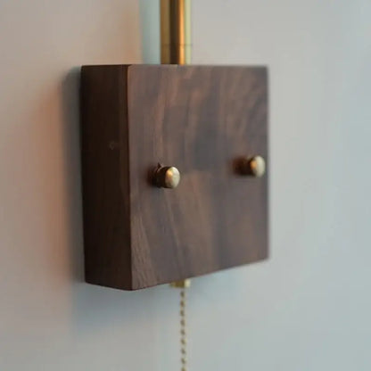 Dark walnut wood wall light switch plate with brass knobs and pull chain complementing decorbites brass led wall light