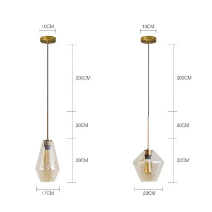 Two modern geometric pendant lights with brass-finished metal and clear glass shades for kitchen lighting