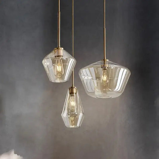 Three geometric glass chandelier pendant lights with brass accents and exposed filament bulbs for kitchen lighting