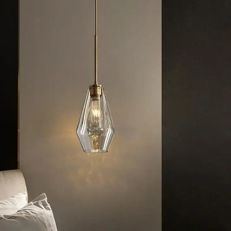 A modern kitchen pendant light with a clear faceted glass shade and brass-toned metal glass chandelier lighting