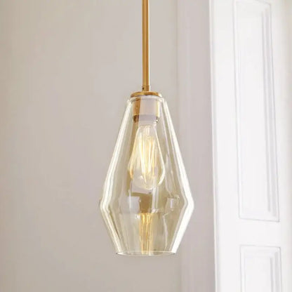 A sleek geometric brass glass pendant lights set featuring faceted glass pendant light and exposed filament bulb for living room