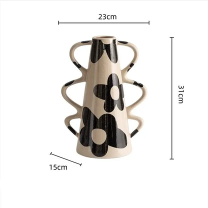 Cream-colored ceramic vase with black floral decals and multiple curved handles complements geometric check pattern decor