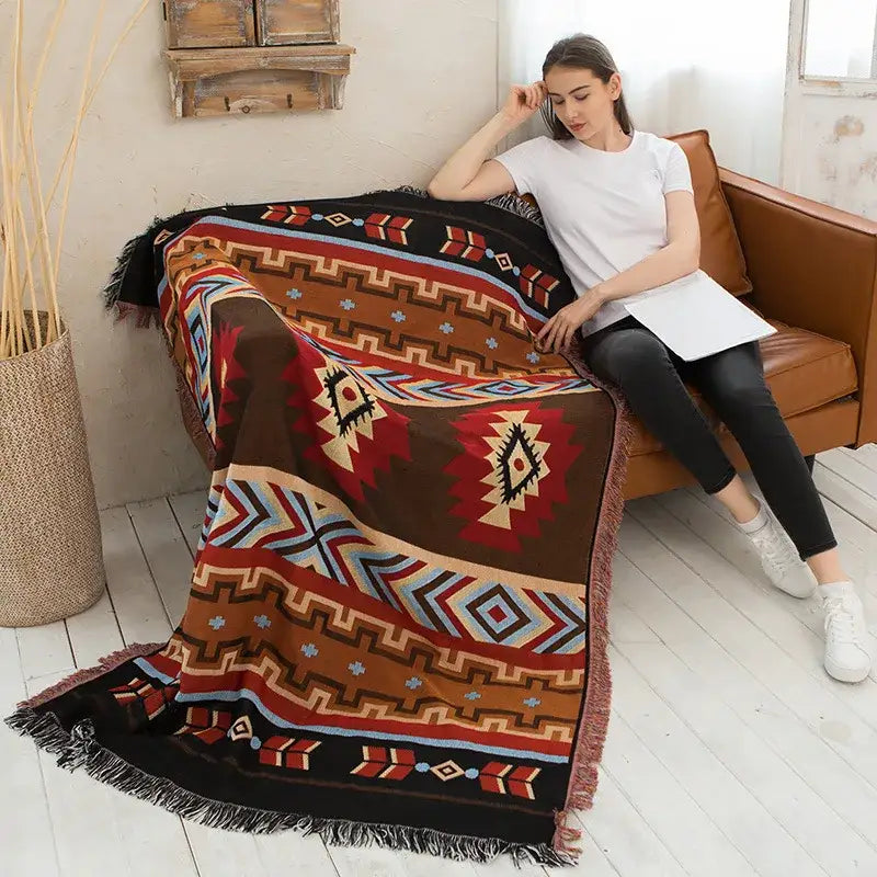 A cozy brown red and beige decorbites geometric cotton knitted sofa blanket with tribal patterns and fringed edges