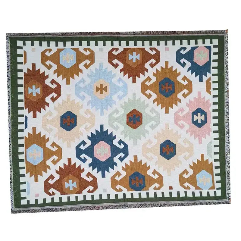 A geometric cotton knitted sofa blanket with earthy brown blue and pink pattern on white background with green fringe