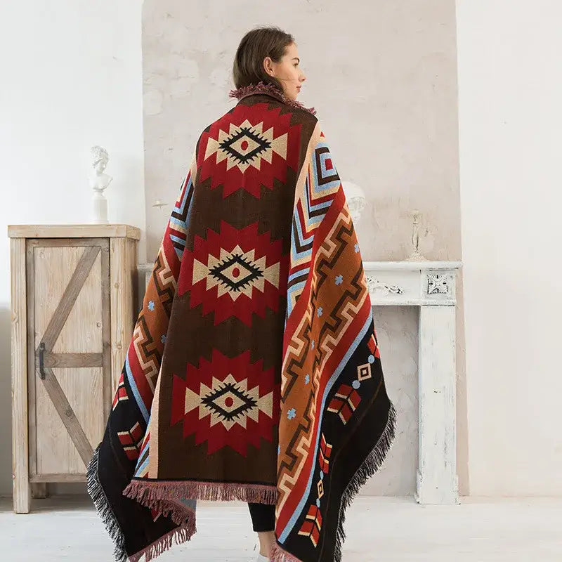 A woman wears a decorbites geometric cotton knitted sofa blanket in red brown and cream for living room decor