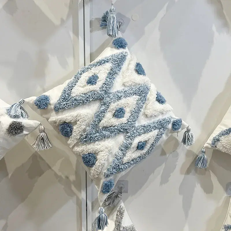 Cream-colored geometric diamond tufted embroidery pillow with soft blue and white yarns and tassels for living room decor