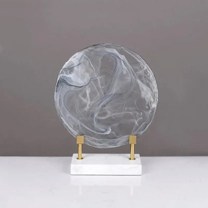 Geometric disk marble clear glass orb in translucent gray and white on marble base with gold supports for home decor