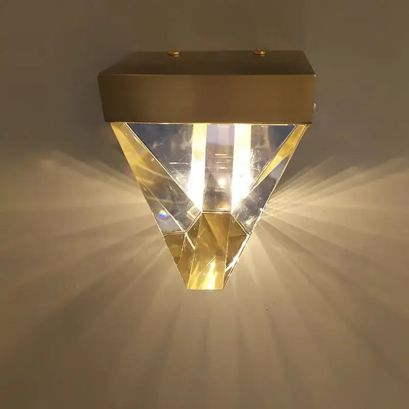 Gold-finished geometric led wall sconce with faceted crystal panels emitting warm light for bedroom decorbites crystal led use