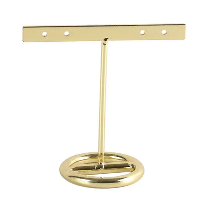 Gold-colored metal geometric jewelry display rack with circular base and horizontal bar for earrings in bedroom use