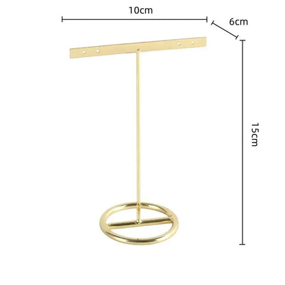 Gold-colored metal geometric jewelry display rack with circular base and horizontal bar for earring organization