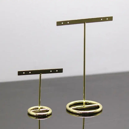 Geometric gold jewelry display rack with metal earring stands featuring circular bases and horizontal bars with holes