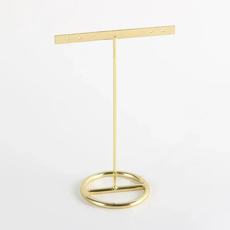 Gold-colored metal geometric jewelry display rack with circular base and horizontal bar for hanging earrings