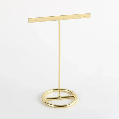 Gold-colored metal geometric jewelry display rack with circular base and horizontal bar for hanging earrings