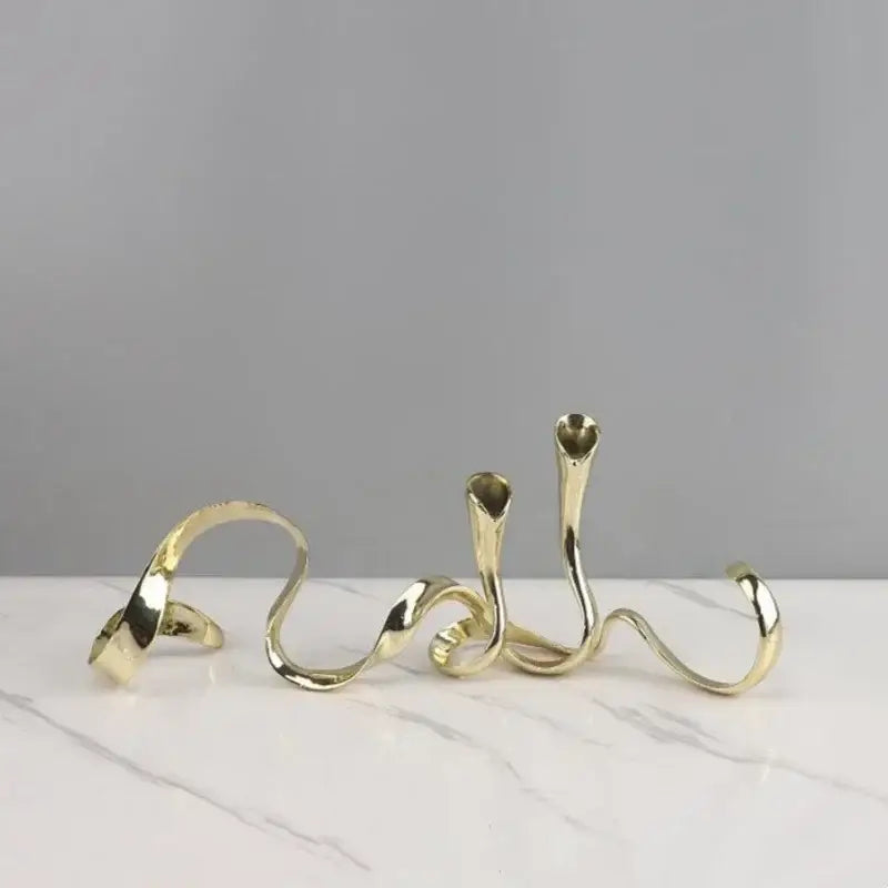 Gold-toned abstractly twisted metal geometric gold candlestick holder with sleek polished curves for dining room decor