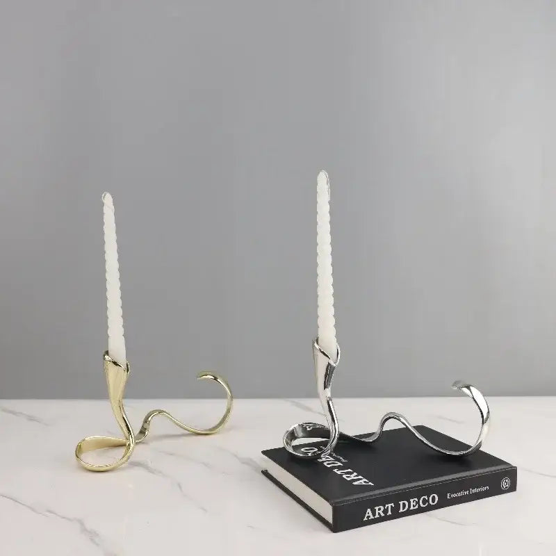 Two elegant geometric gold and silver candlestick holders with white textured taper candles for dining room decorbites centerpiece