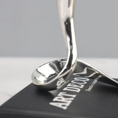 Shiny silver spoon-shaped sculpture as part of decorbites geometric gold and silver candlestick holder centerpiece