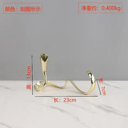 A sleek gold-toned metal candlestick holder with an elegant twisted design for decorbites geometric gold centerpiece