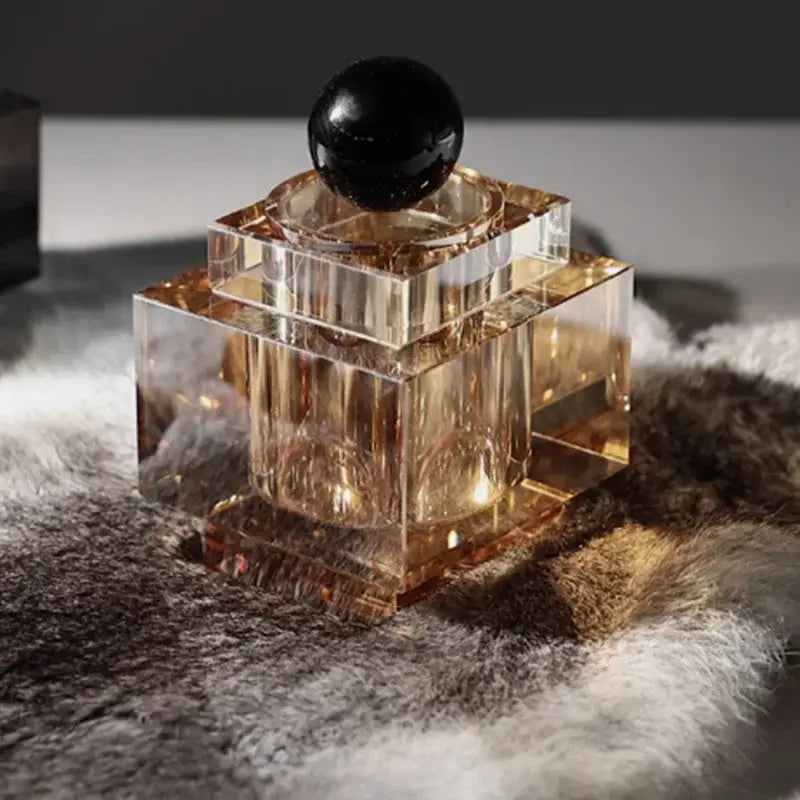 A sleek crystal storage jar with faceted amber glass and glossy black stopper for bedroom decor