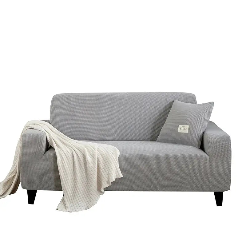 Geometric gray textured stretch sofa cover with matching pillow and cream ribbed throw blanket in living room setting