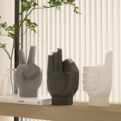 Three minimalist geometric hand sculptures in matte gray black and white for gesture art decor on a wooden shelf