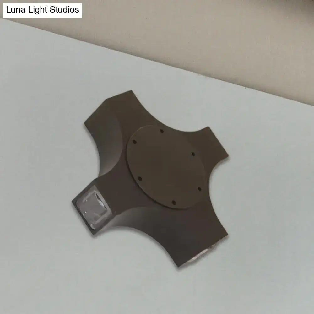 Dark brown four-spoked hubcap with circular mounting plate and holes for geometric metallic shade bronze wall sconce