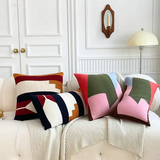 Three colorful geometric multi color knitted cushion cover set with bold stripes on a cream sofa for living room decor