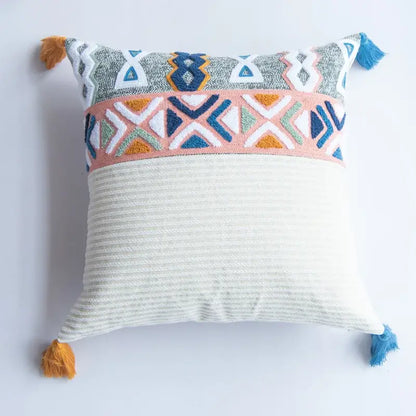 Square embroidered cushion cover with multicolor geometric patterns and tassels on an off-white ribbed base