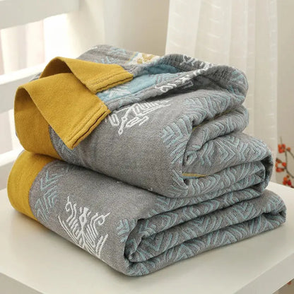 Stacked gray and mustard yellow cotton gauze summer blankets with embroidered geometric patterns from decorbites cotton gauze collection