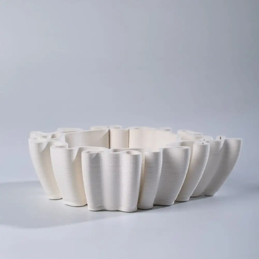 Geometric off white ceramic flower pot sculpture with sculpted petal design and vertical ribbed texture for living room decor