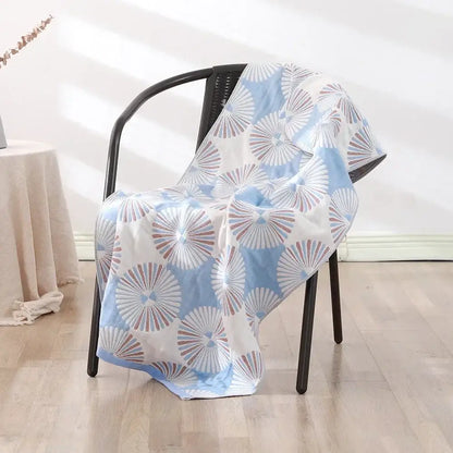 A light blue and white cotton bath towel with fan-shaped pattern draped on black wicker chair for decorbites cotton bath use