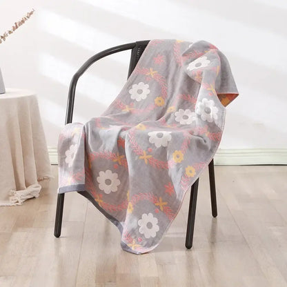 Gray floral-patterned decorbites cotton bath towel with white yellow and pink blossoms draped over a black chair