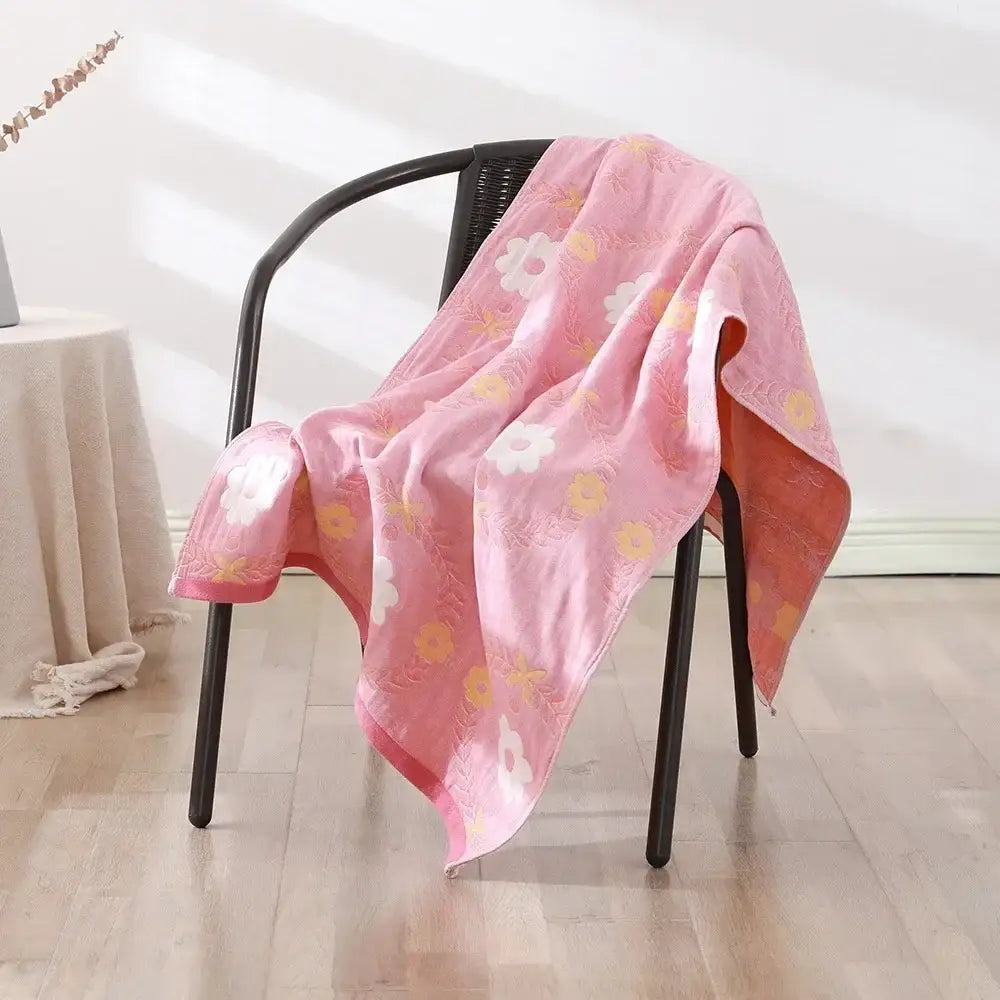 A soft pink decorbites cotton bath towel with embroidered floral patterns draped over a black chair for quick dry use
