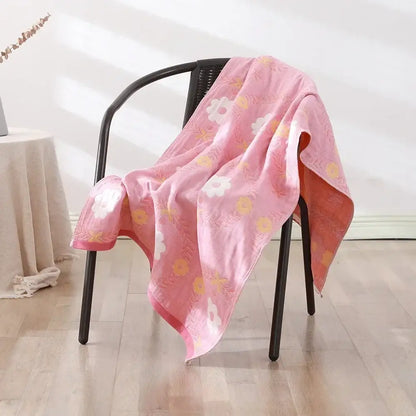 A soft pink decorbites cotton bath towel with embroidered floral patterns draped over a black chair for quick dry use