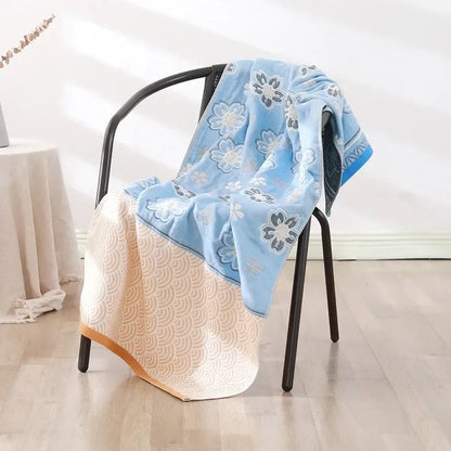 A two-toned light blue and cream decorbites cotton bath towel with embroidered floral and wave patterns