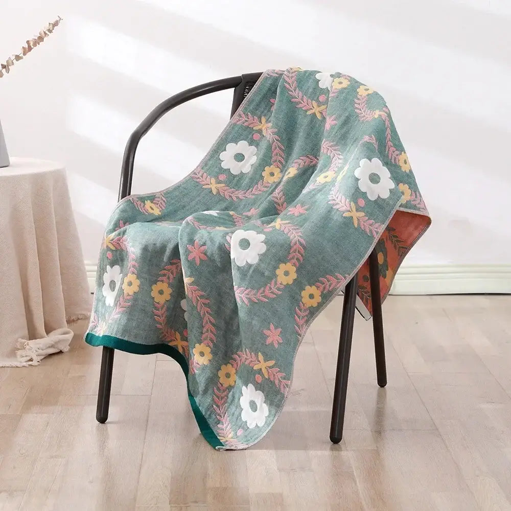 A soft teal cotton bath towel with floral pattern draped over black chair from decorbites cotton bath collection