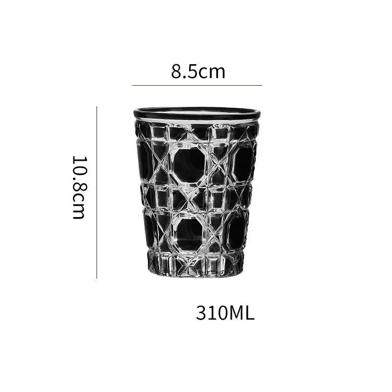 A clear glass tumbler whiskey glass with a black rim and diamond cut facets in red green and amber colors