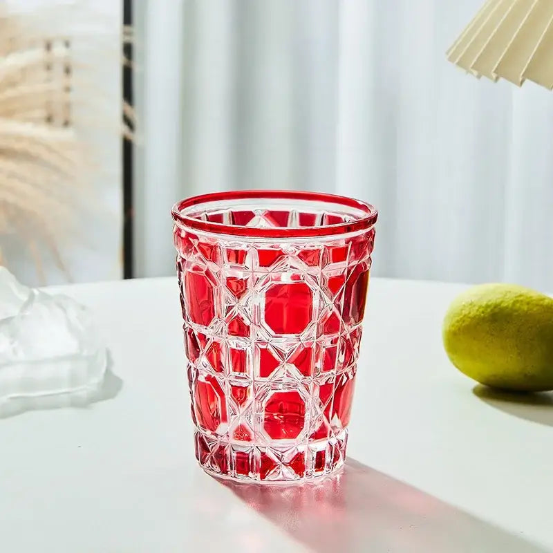 A vibrant red geometric glass tumbler with faceted design and clear accents heavy whiskey glass for dining room use