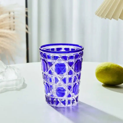 A vibrant cobalt blue glass tumbler with a geometric faceted pattern heavy whiskey glass for dining room use