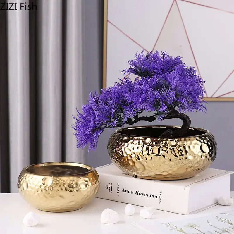 Golden hammered ceramic bonsai pot with vibrant purple artificial tree atop minimalist ceramic vase decorbites design