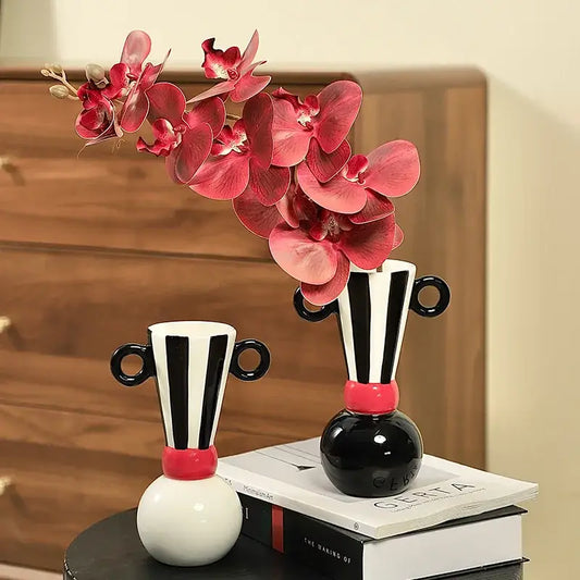 Black and white geometric stripes ceramic vase with red handles holding pink orchids for living room decorbites decor
