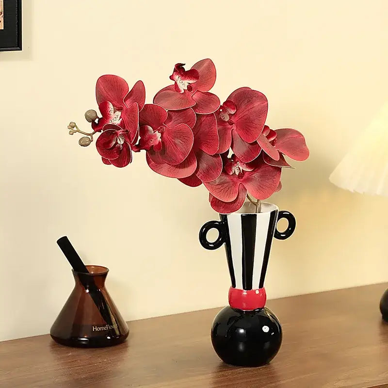 Black and white ceramic vase with red accents and handle-like ears featuring geometric stripes for living room decor